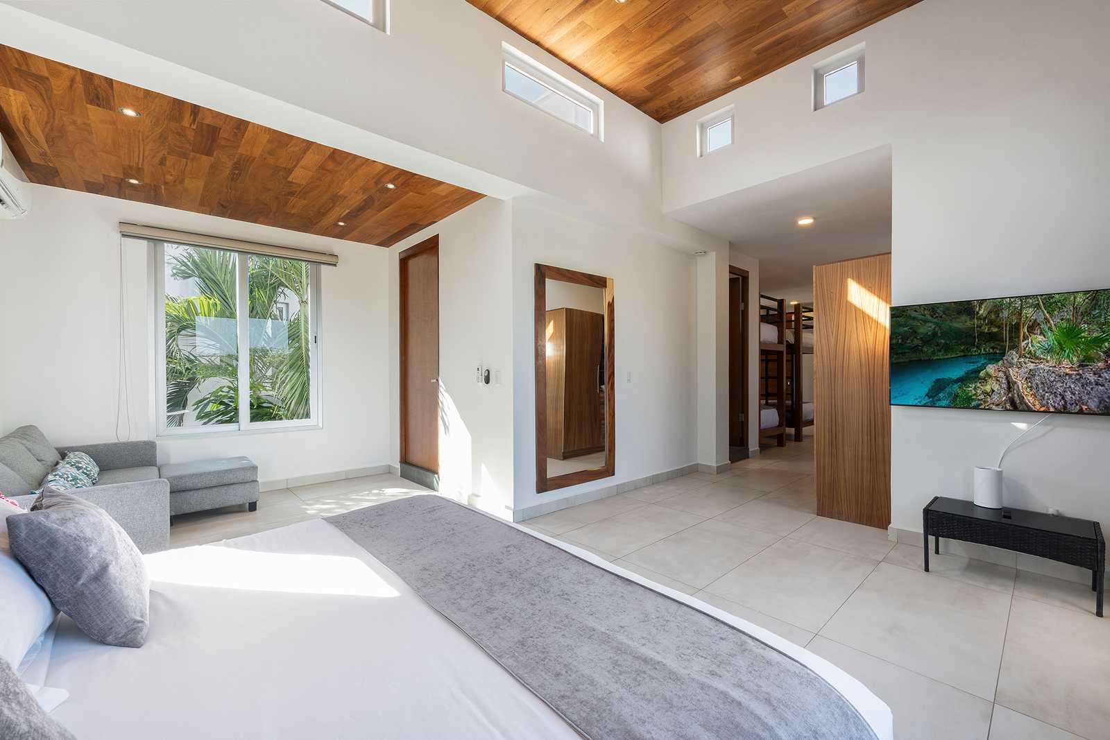 Modern luxury bedroom with lounge seating and natural light at Villa Hurakán