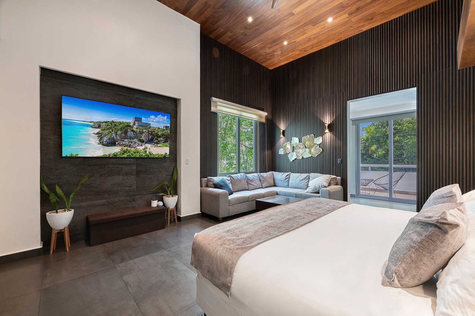 Luxury dark-tone bedroom suite with lounge seating at Villa Hurakán