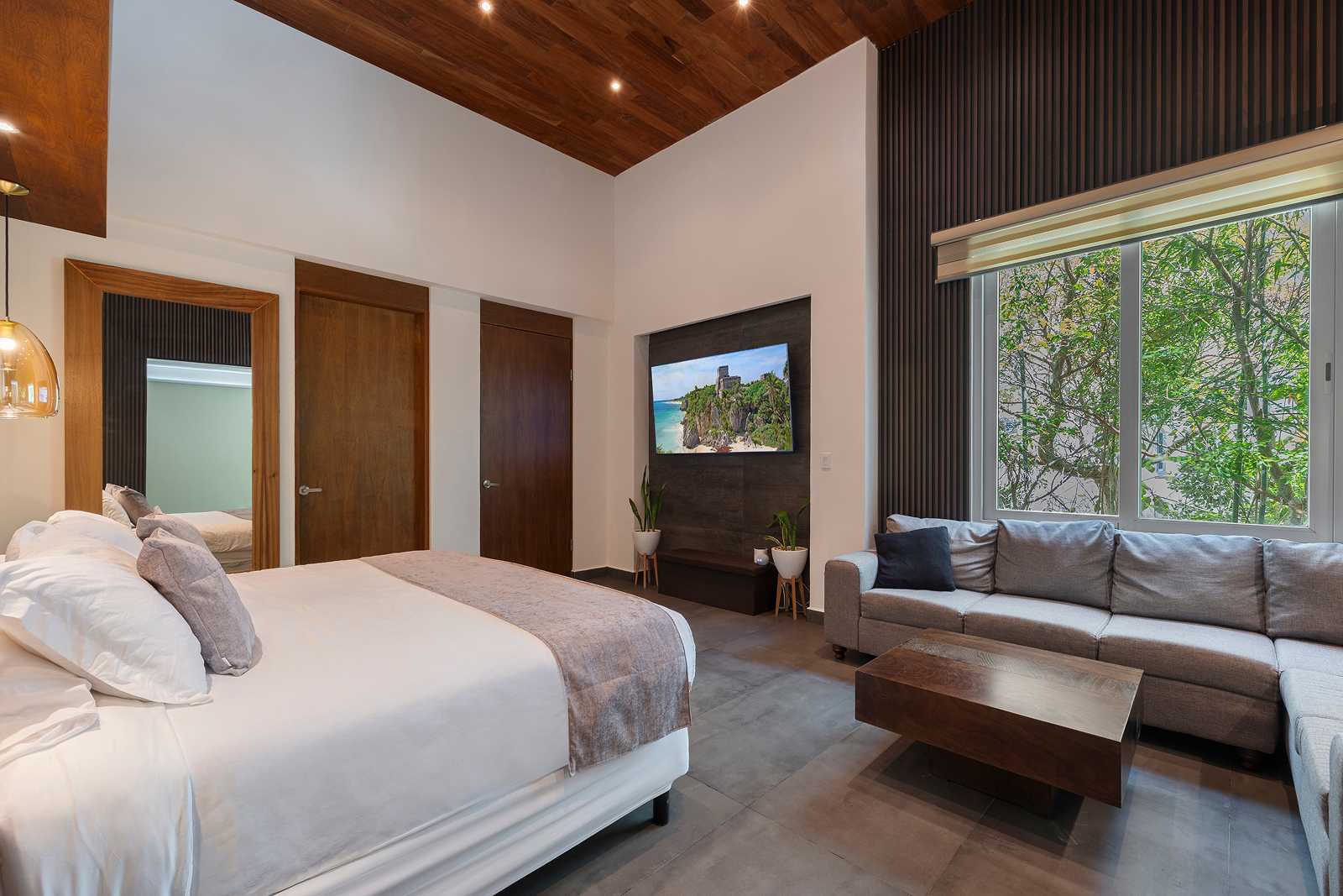 Spacious luxury bedroom with lounge area and jungle-facing windows at Villa Hurakán
