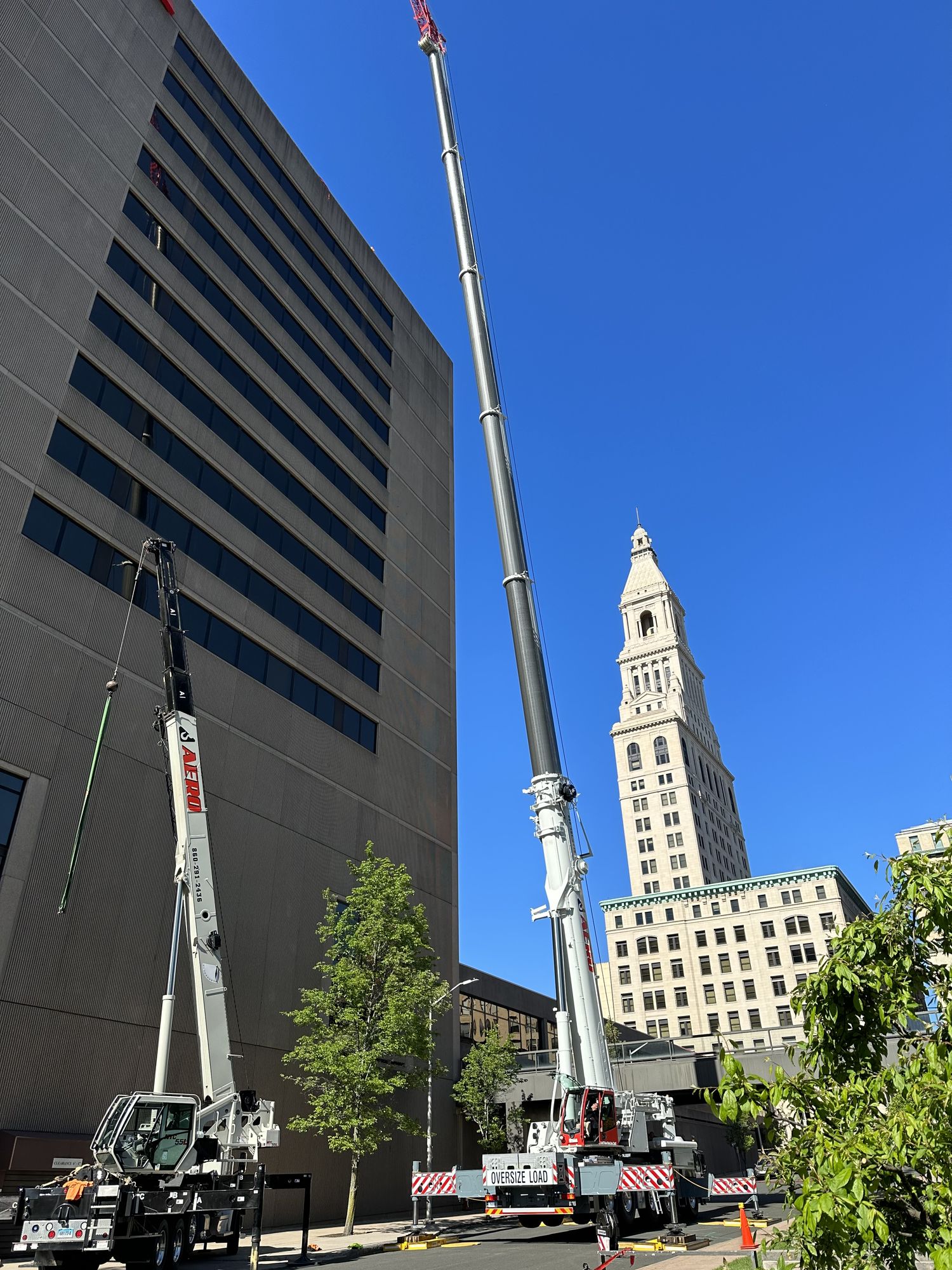 Operated crane with extended boom at downtown building lift