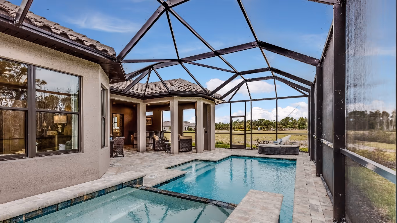Enclosed outdoor pool area of a Florida home with lounge chairs and seating under screened roof.