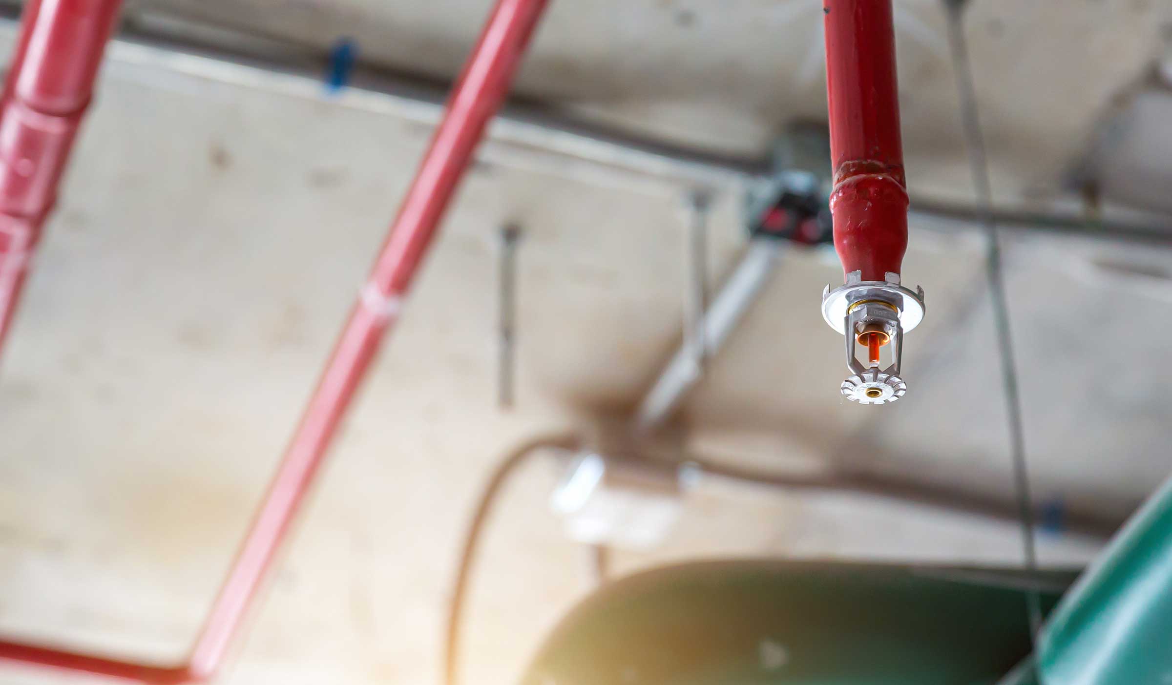 a lone sprinkler spout with pipes in the background