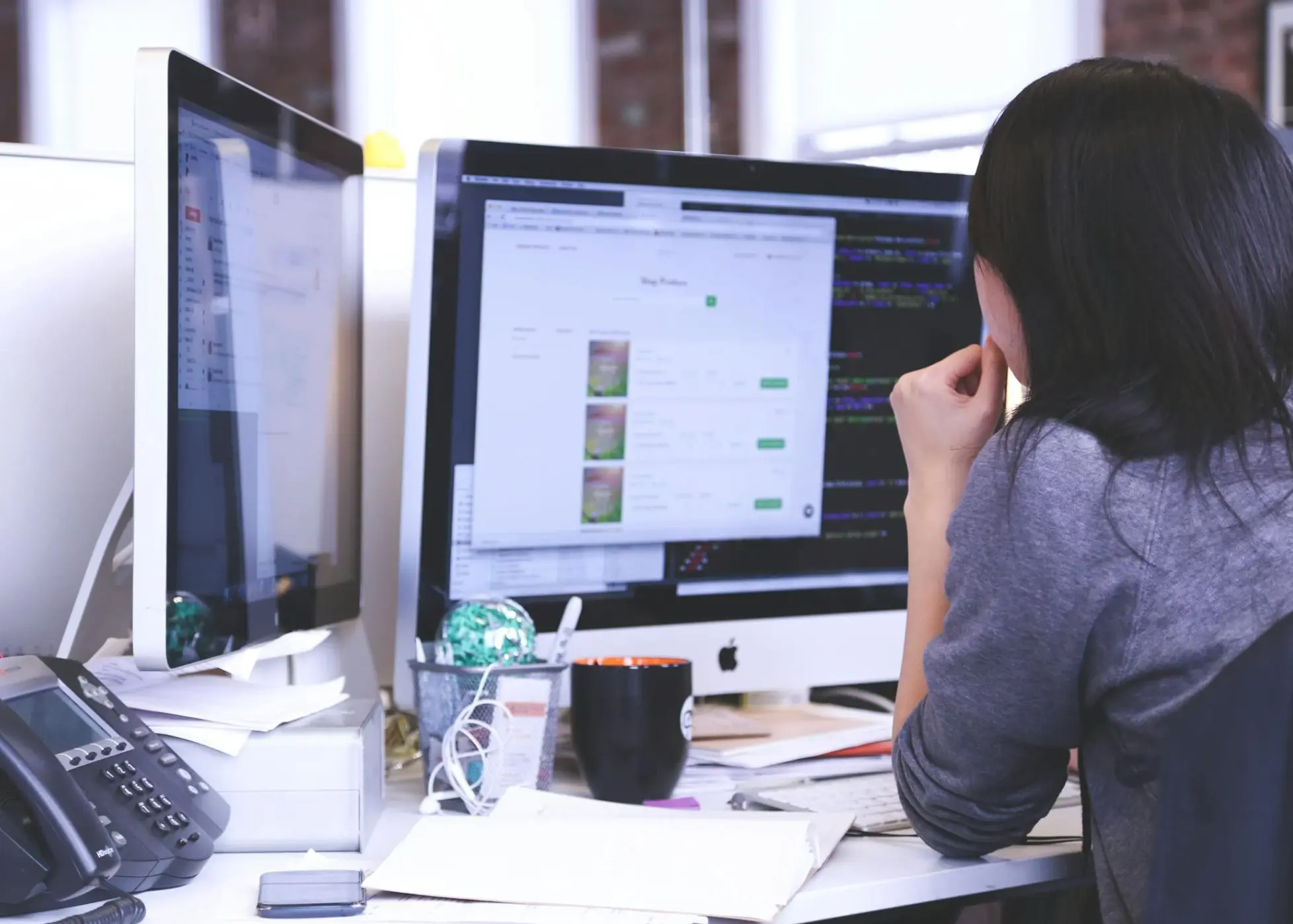 woman looking at two PC screens