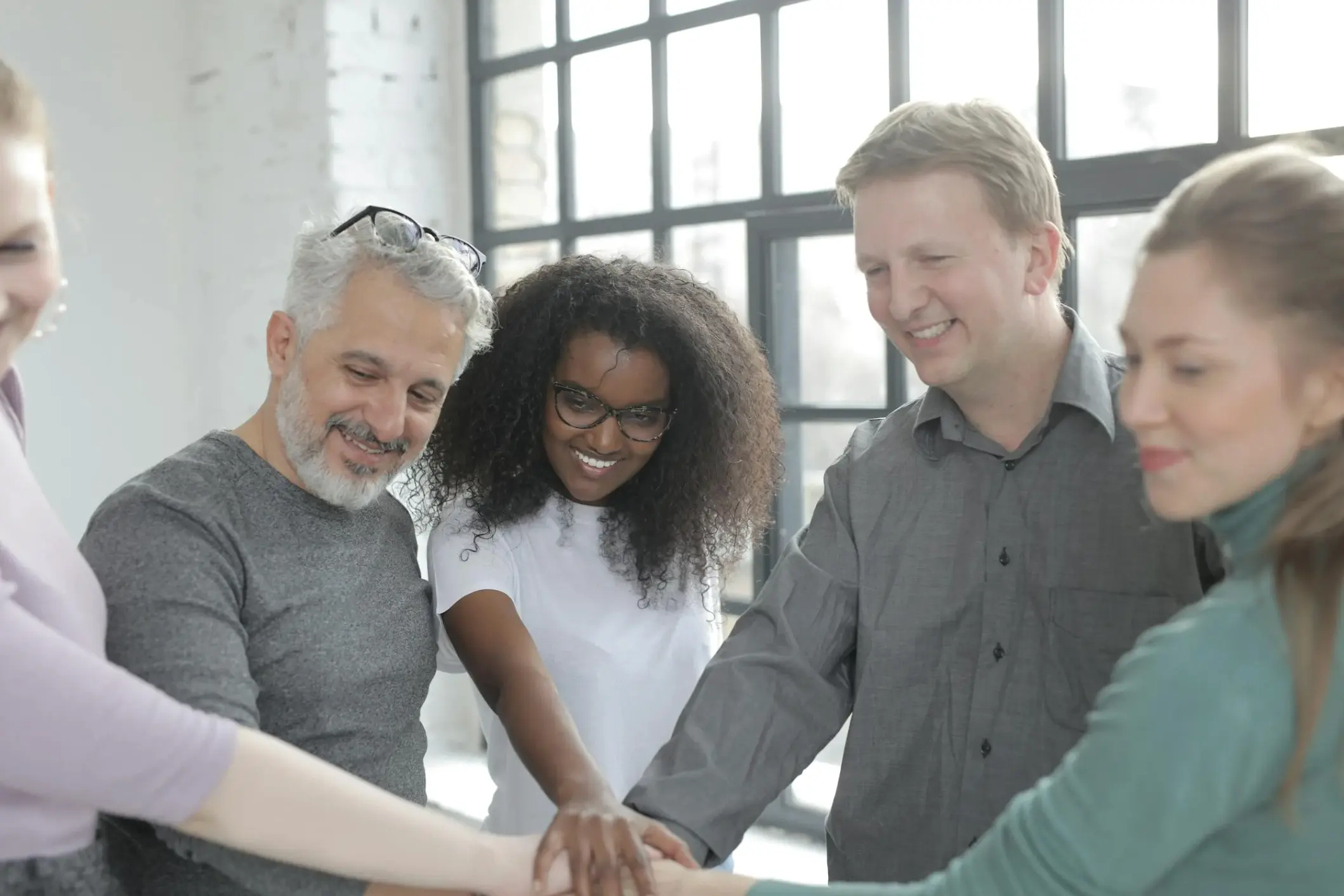 Happy colleagues joining hands at work
