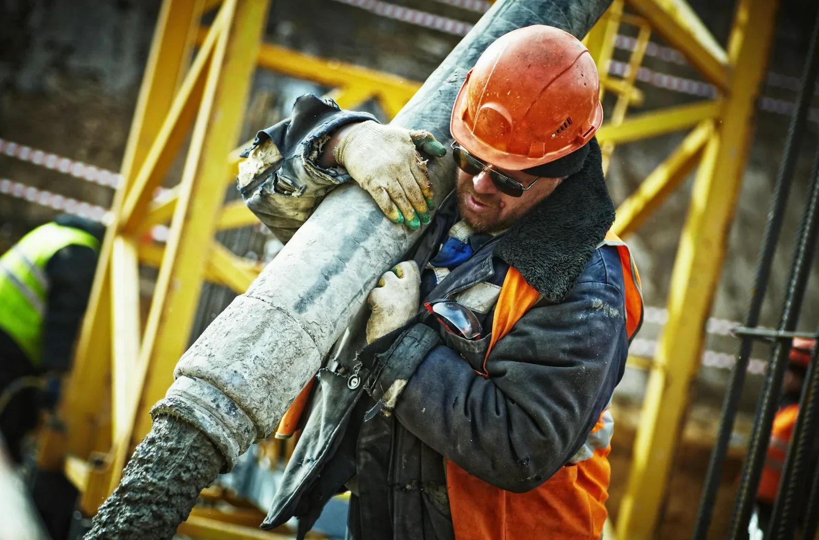 construction worker carrying pipe