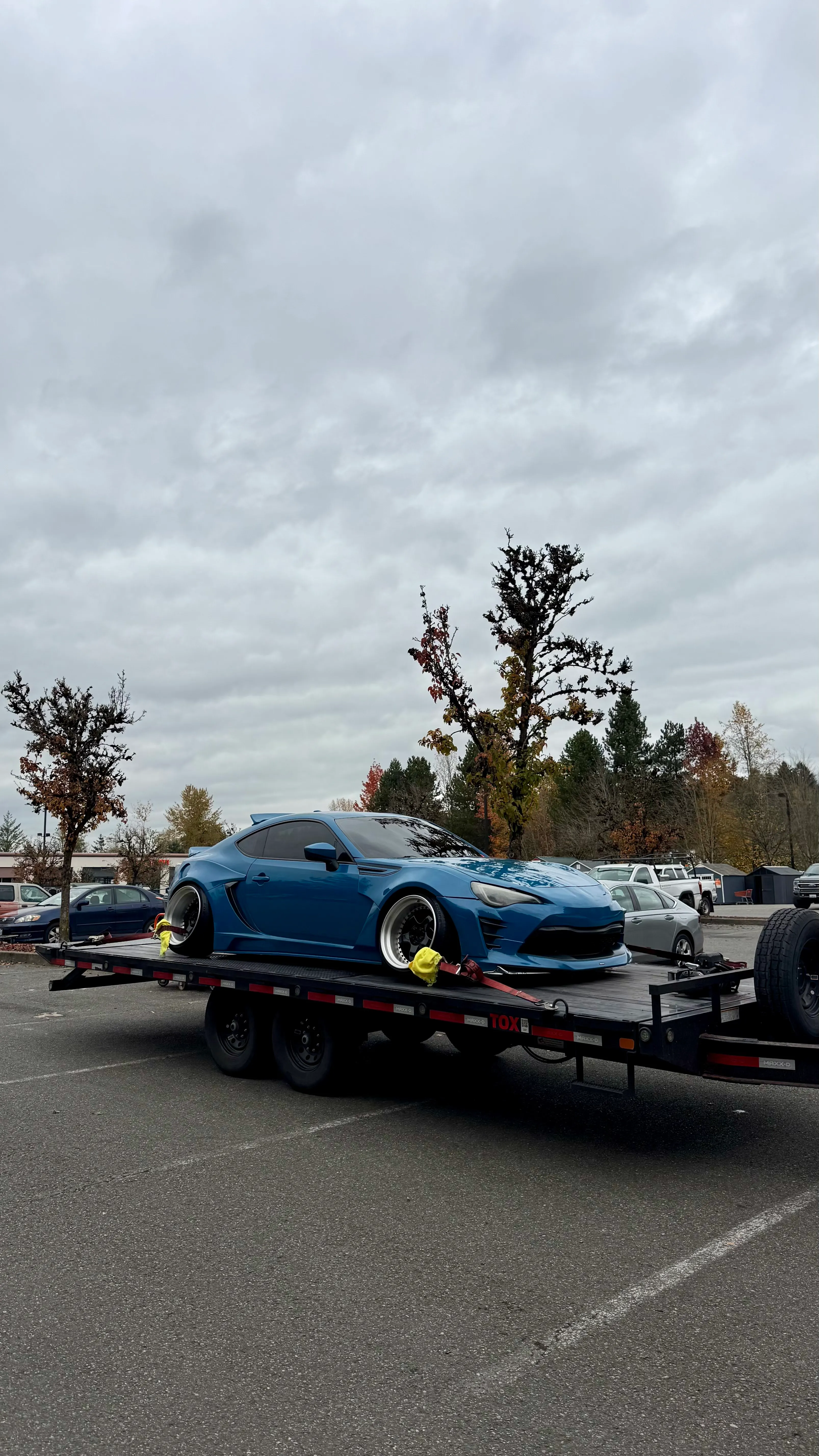 Blue widebody sports car on an OTG drive-over-fender car hauler
