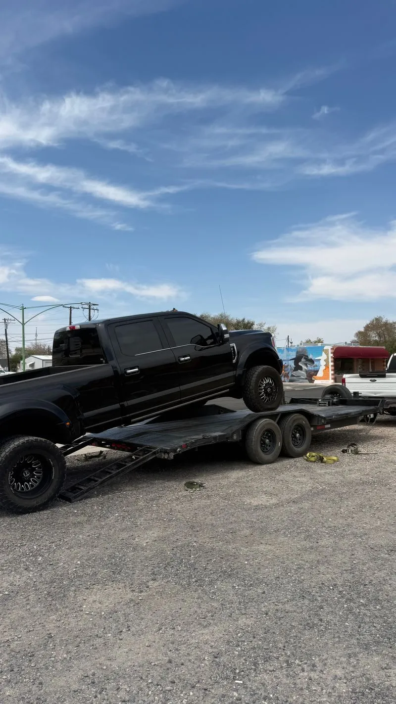 Black Ford F-450 dually loading onto the OTG drive-over fender car hauler