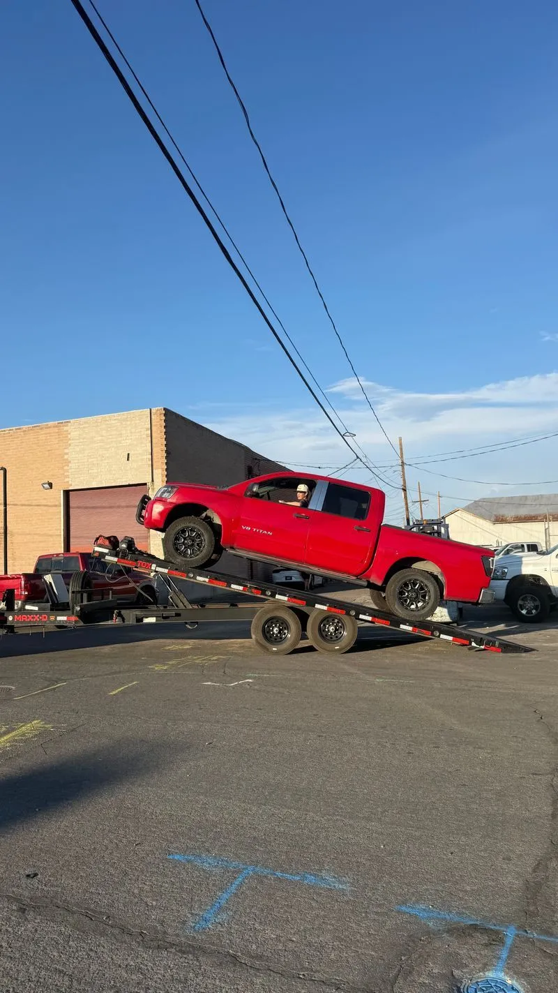 Red Nissan Titan driving up the OTG deckover tilt trailer