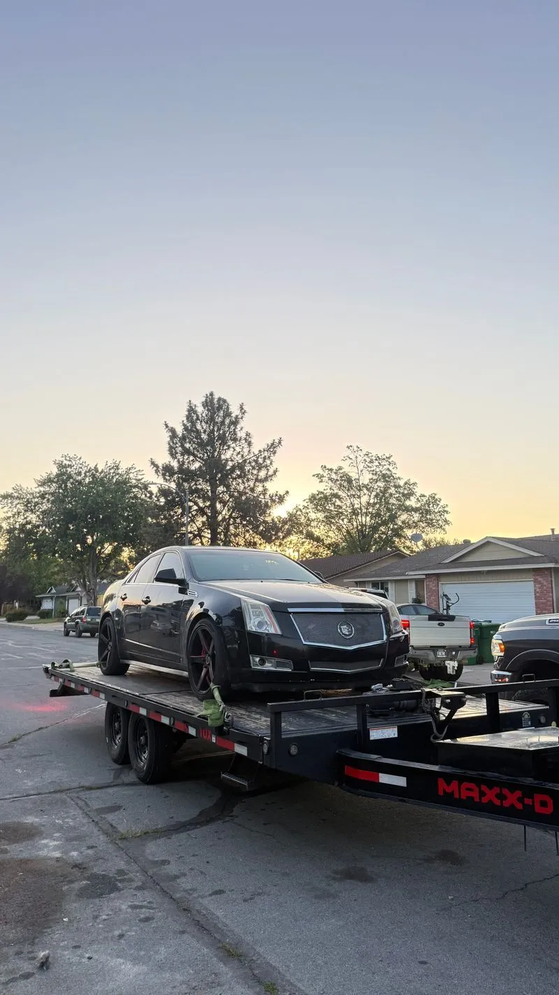 Black Cadillac CTS on the OTG deckover tilt trailer at sunset