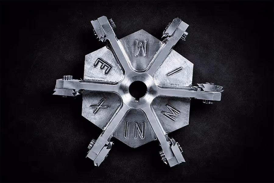Herramienta metálica industrial con cabeza hexagonal y seis brazos marcados con letras I, N, M, I, M, E y X.