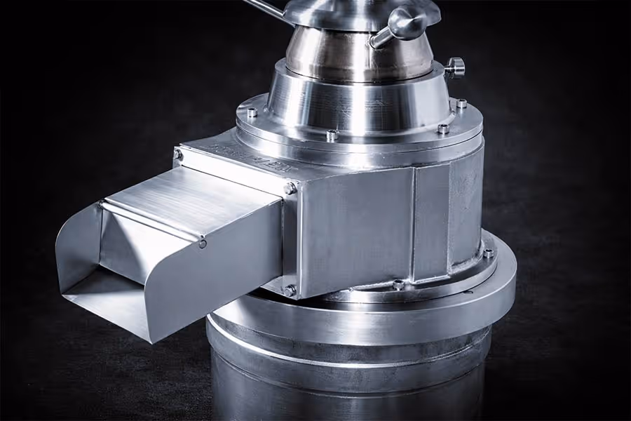 Parte metálica pulida de una máquina industrial con una boquilla rectangular sobresaliente.