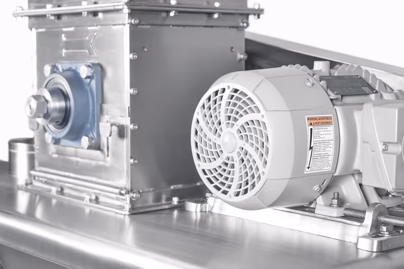 Motor eléctrico gris conectado a un molino de cuchillas de acero inoxidable.