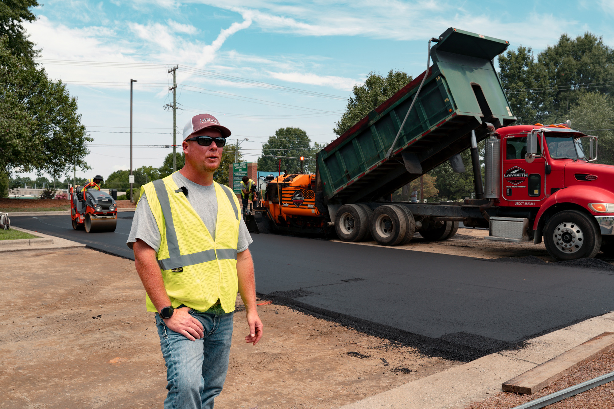 Jordan Lambeth on a commercial paving job as the crew lays asphalt behind him