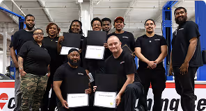Group of ten people in black shirts posing indoors, three hold certificates, all smiling.