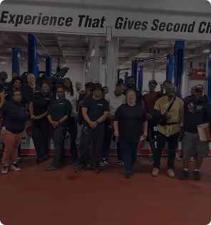 Group of diverse people standing in a gym with pillars and equipment behind them.