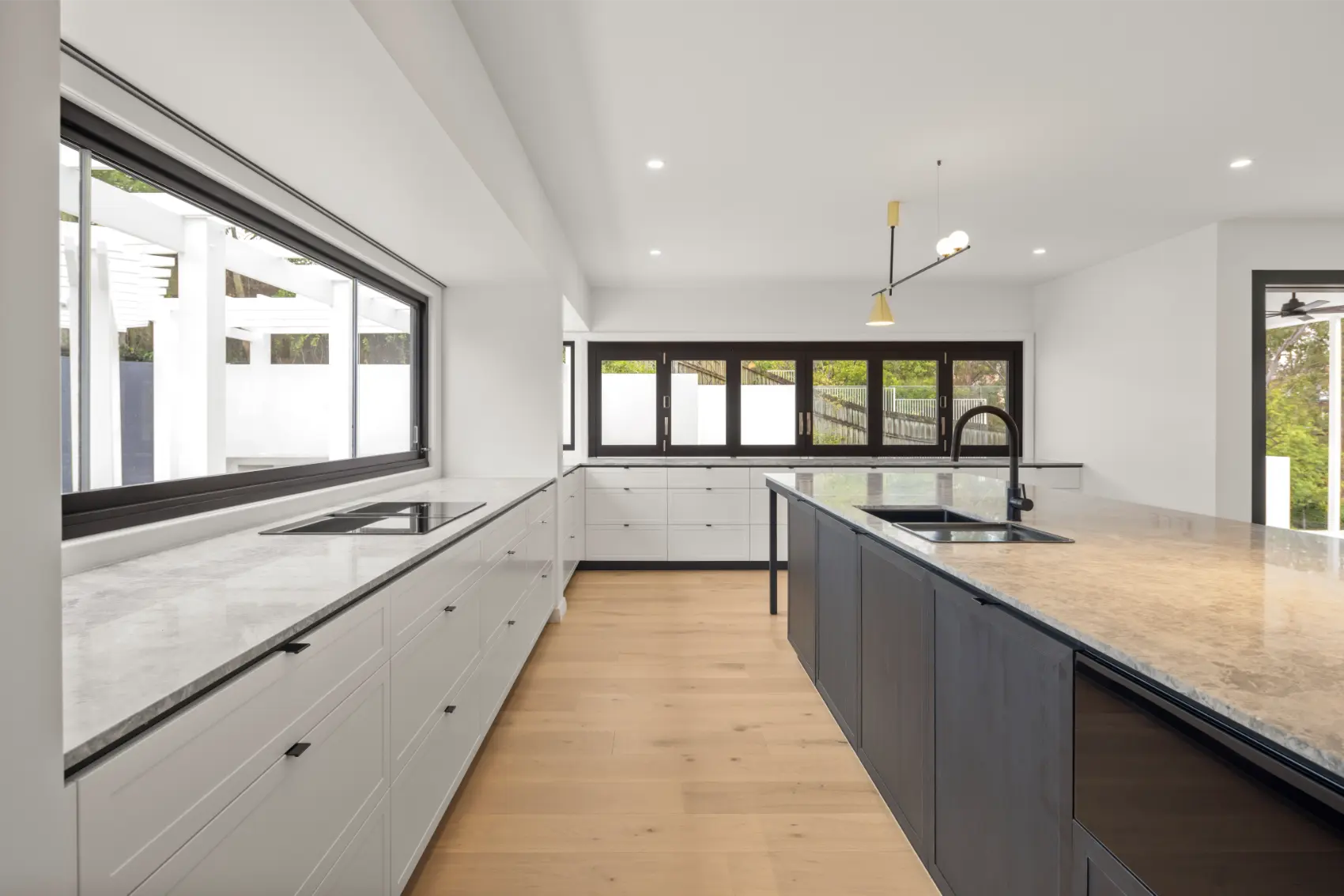 Modern kitchen interior with stone benchtops and large windows in a high-end Brisbane residential project.