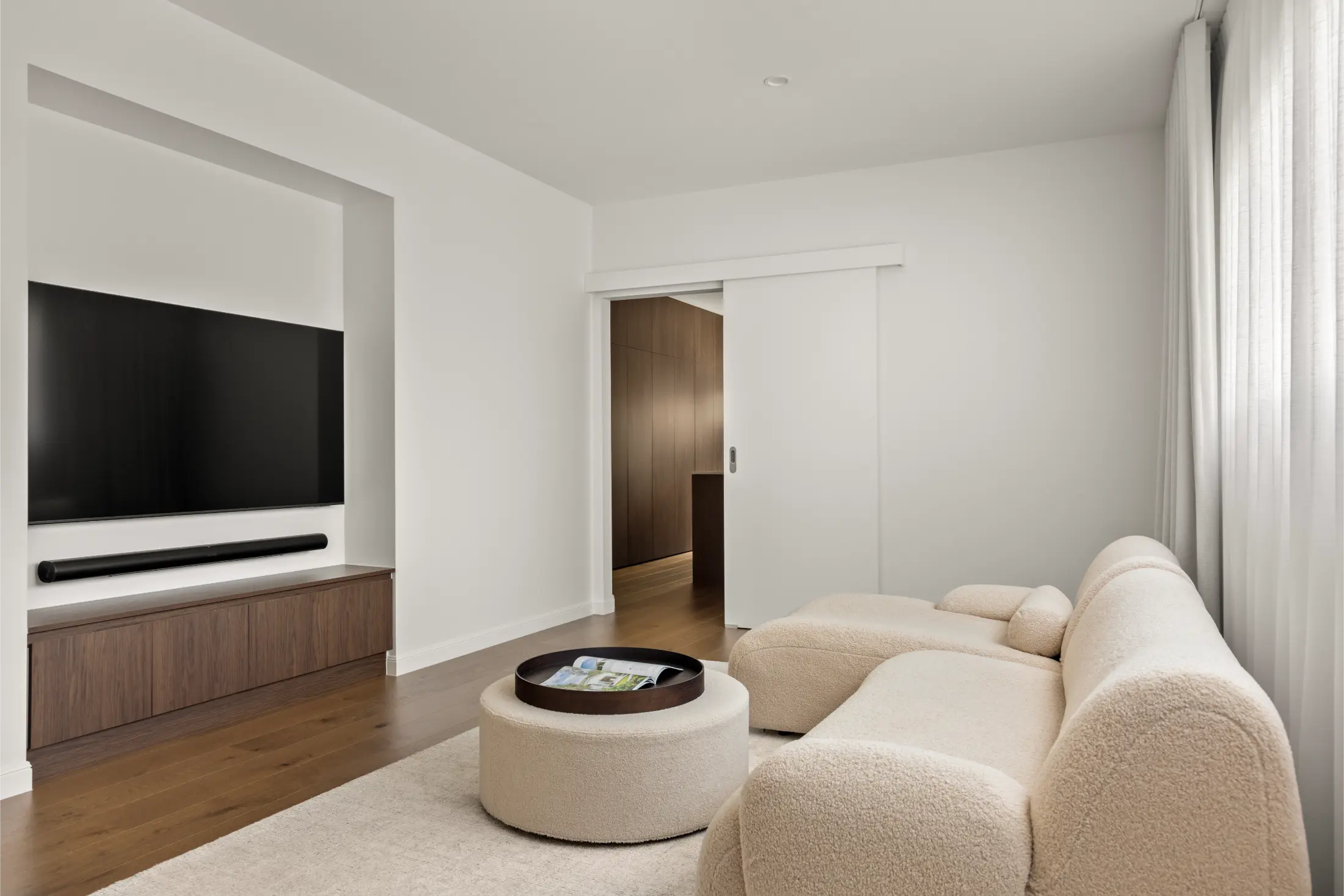 Modern living room with built-in television, neutral furnishings, and contemporary finishes in a high-end Brisbane residential project.