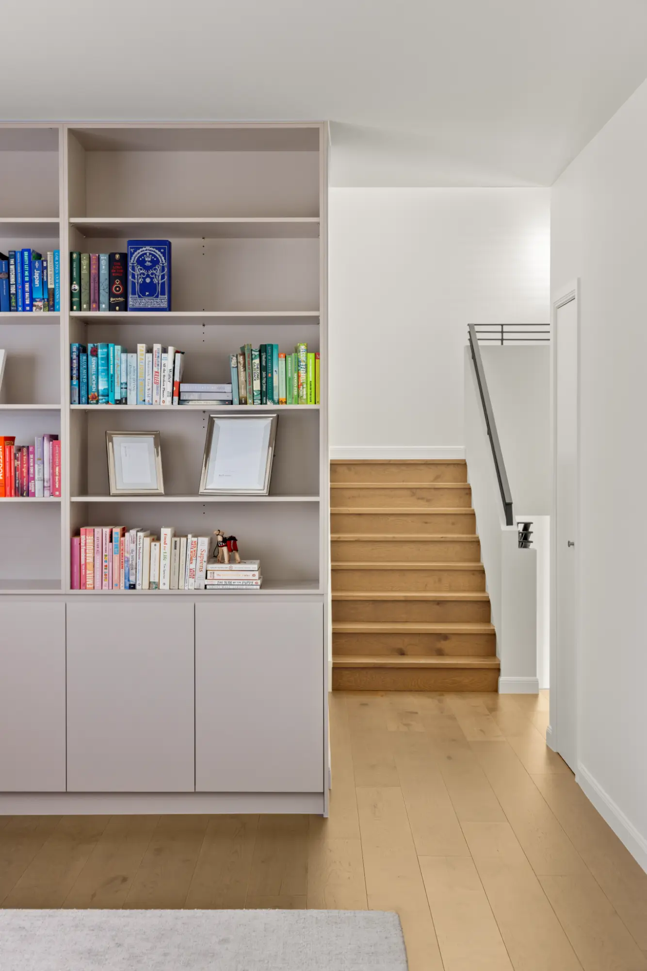 Modern staircase with built-in bookshelf and contemporary interior finishes in a high-end Brisbane residential project.