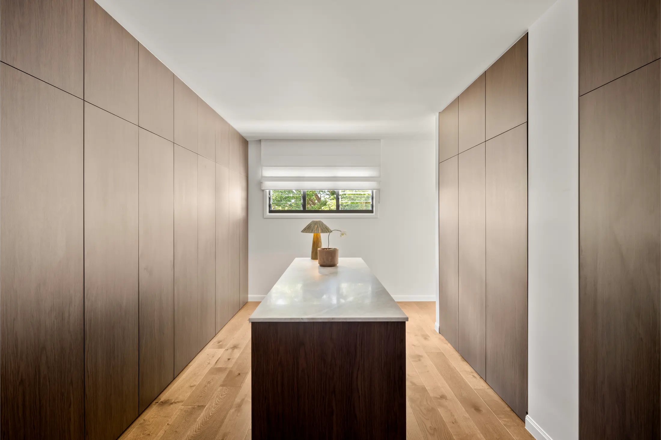 Modern hallway with timber wall panelling and a central stone island in a high-end Brisbane residential project.