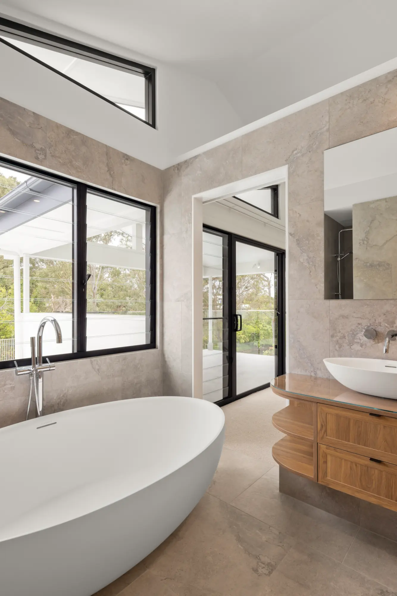 Modern bathroom with a freestanding bathtub, stone finishes, and timber vanity in a high-end Brisbane residential project.
