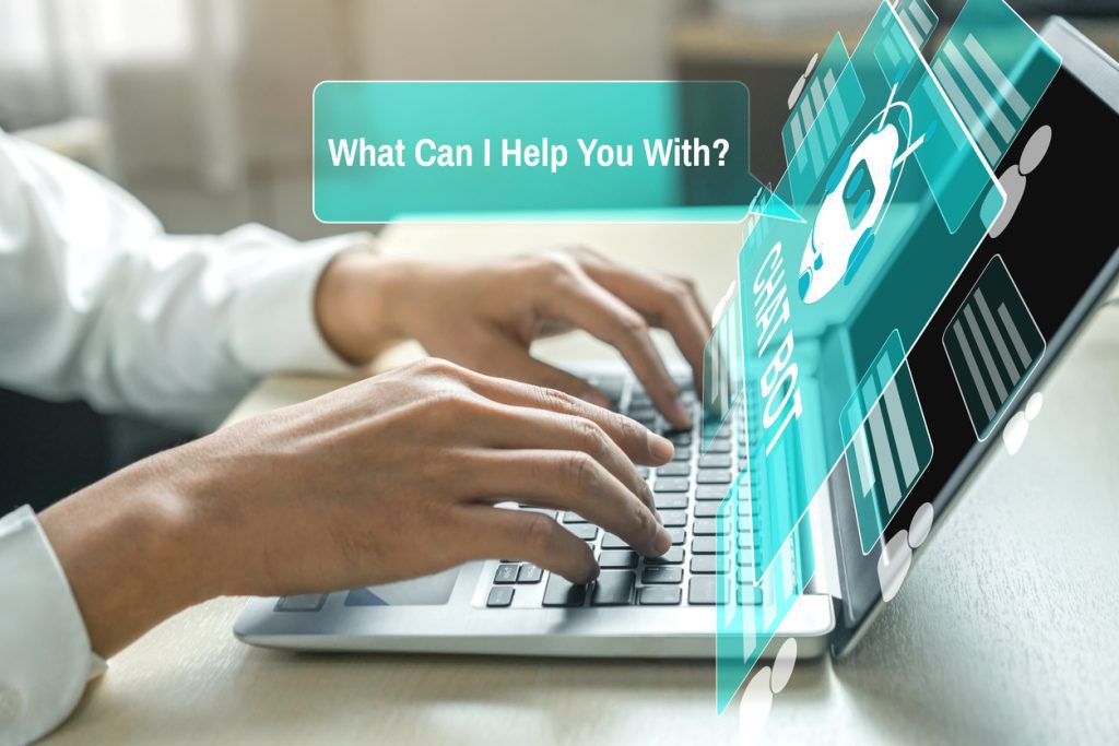 A person typing on a laptop with an AI Concierge interface on the screen displaying the message, What Can I Help You With?.