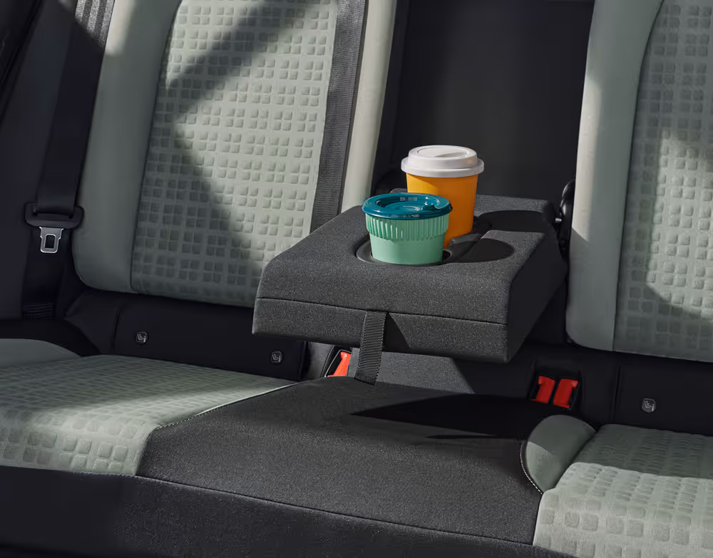Blick auf die Rücksitze des Škoda Epiq. Aus der Rückenlehne des mittleren Sitzes ist eine dunkelgraue Armlehne heruntergeklappt, die als praktischer Cupholder für zwei Becher dient.