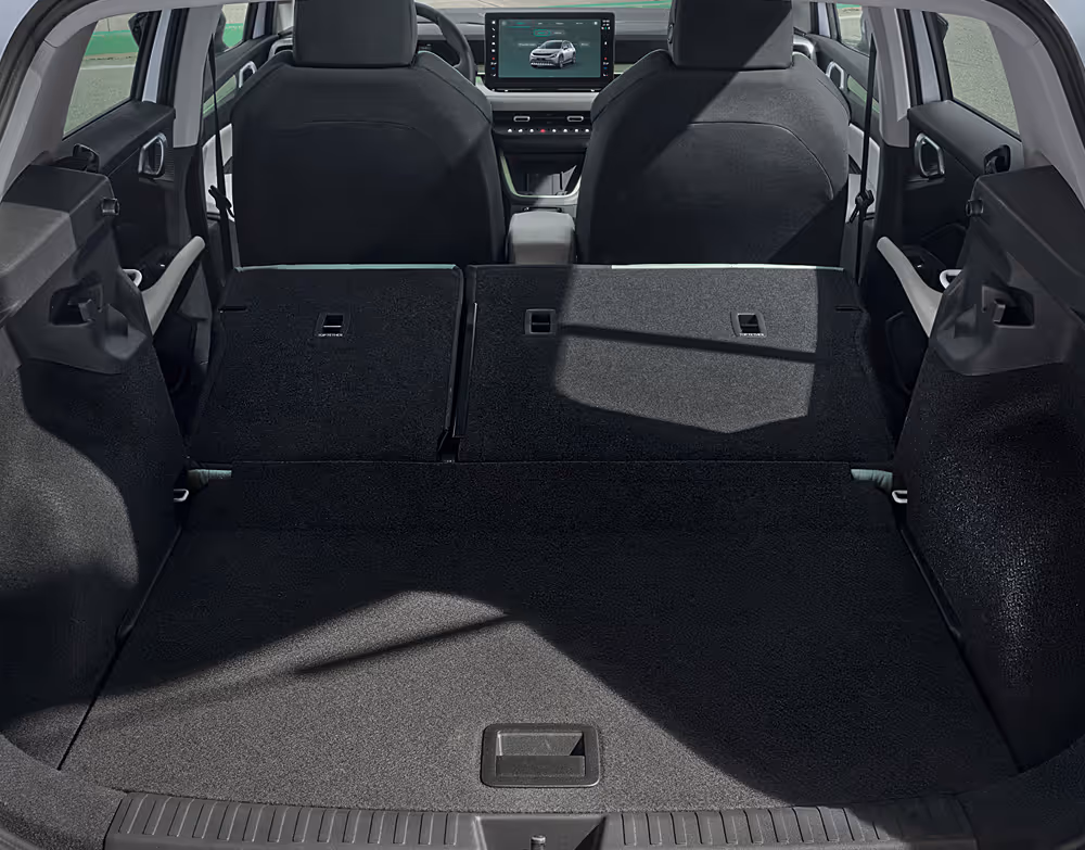 Blick in den geöffneten Kofferraum des Škoda Epiq mit komplett umgeklappten Rücksitzen. Es zeigt sich ein ebenes, mit dunklem Teppich ausgekleidetes Ladeabteil, das freien Blick bis nach vorne auf das Armaturenbrett mit dem zentralen Infotainment-Display bietet.