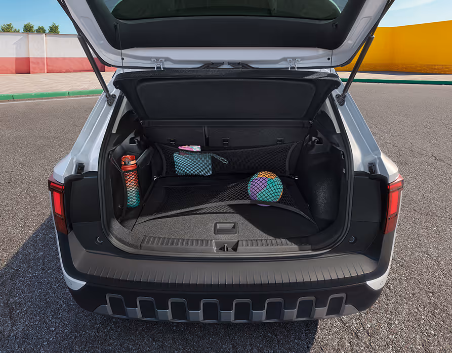 Blick in den geöffneten Kofferraum des Škoda Epiq in Platinum-Weiß Metallic, der mit verschiedenen Gepäcknetzen ausgestattet ist. Ein bunter Ball wird sicher von einem Bodennetz fixiert, während eine Trinkflasche und eine kleine Tasche in den seitlichen und hinteren Netzen verstaut sind.