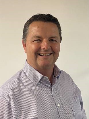 Portrait of a smiling middle-aged man wearing a light purple striped button-up shirt
