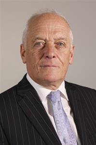 Older man in dark pinstriped suit with lavender tie and white shirt