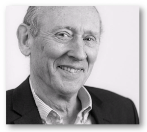 Black and white portrait photograph of an elderly man with gray hair smiling warmly at camera wearing business attire