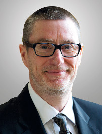 Professional headshot of a man wearing glasses and business attire