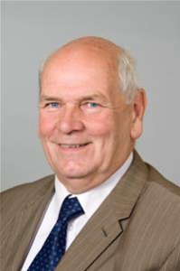 Professional headshot of older man in gray suit and blue tie