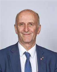 Professional headshot of a middle-aged man in navy blazer and tie