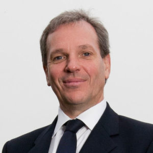 Professional headshot of middle-aged man in dark suit and tie