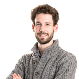 Smiling man with beard wearing gray cardigan, arms crossed, against white background