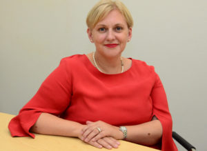 Woman with blonde hair wearing red shirt smiling at camera