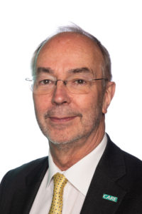Professional headshot of middle-aged man in business suit and glasses.
