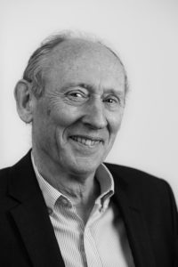 Smiling older man with receding hair wearing dark jacket and white shirt