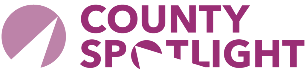 County Spotlight logo with purple circular design and text