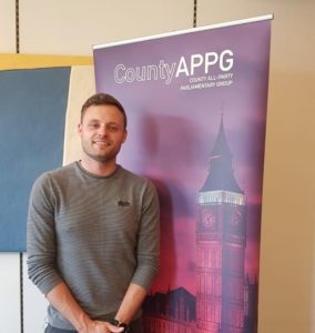 Man smiling in front of County APPG banner with Big Ben building graphic
