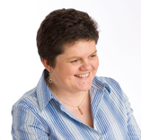 Middle-aged woman with dark hair wearing a blue striped shirt, smiling at camera