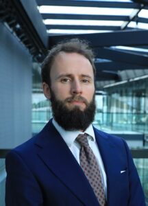 Professional man with beard wearing navy blazer and tie in modern office building