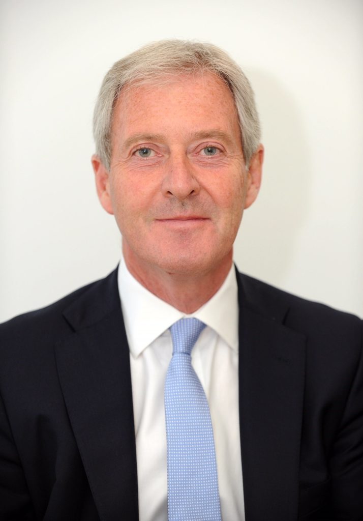 Older man with gray hair wearing dark suit and blue tie portrait