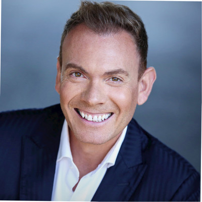 Professional headshot of smiling man wearing navy blazer and white shirt