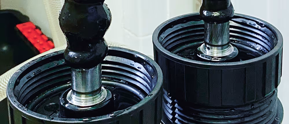 Two adjustable dumbbells placed vertically on a surface, with black weight plates and silver center parts.