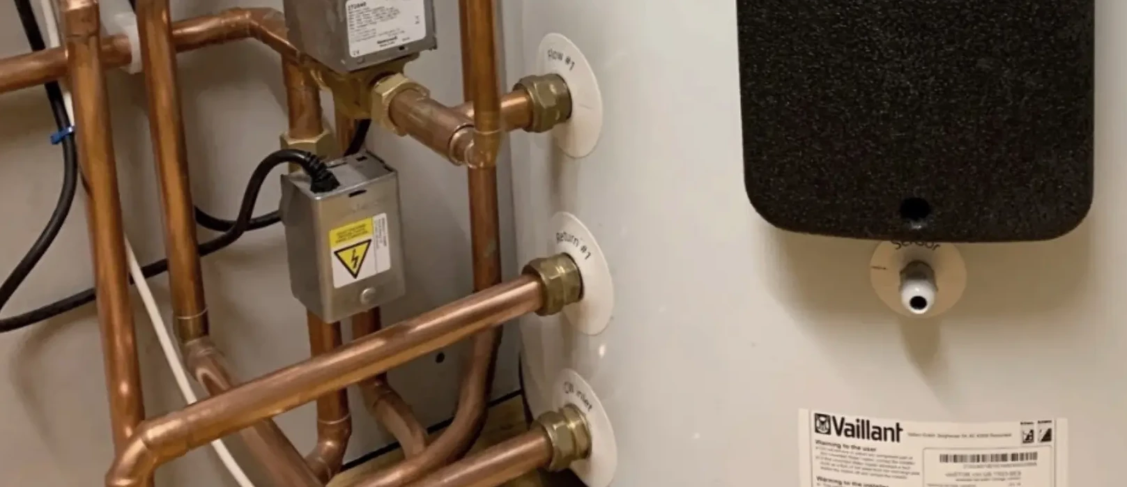 Pipes and valves connected to a white water heater, featuring a Vaillant label.