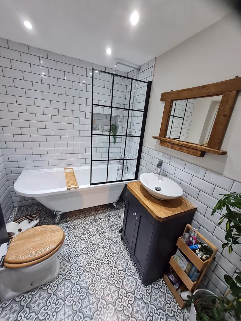 Bathroom with a bathtub, wooden toilet seat, and a sink on a wooden cabinet.