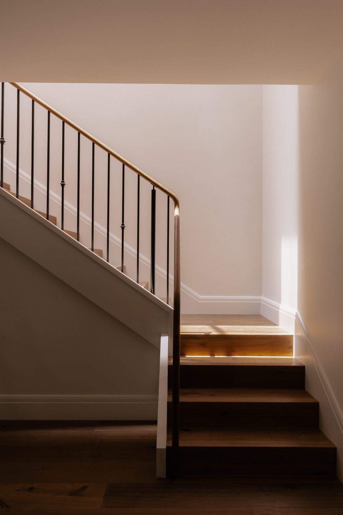Toorak House staircase with timber treads, iron balustrade and recessed lighting beneath each tread, contemporary residential interior design Melbourne