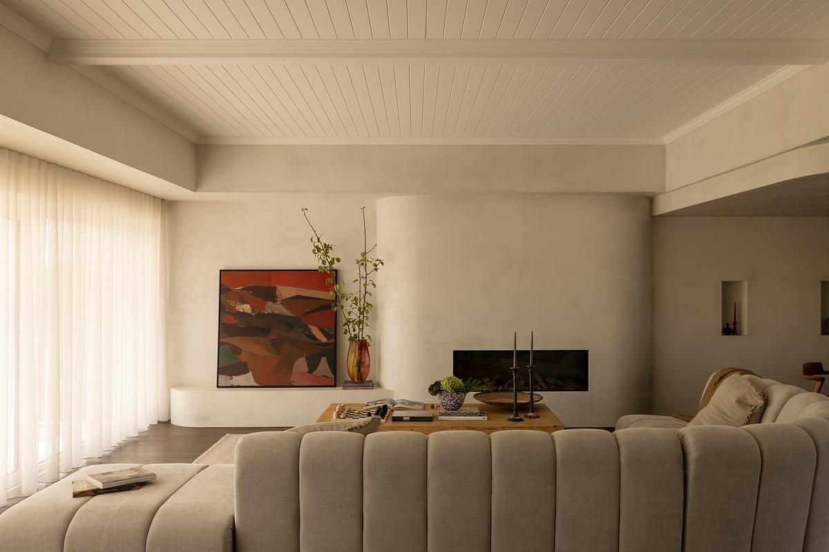 Living room with curved plaster fireplace, channeled sofa and abstract artwork